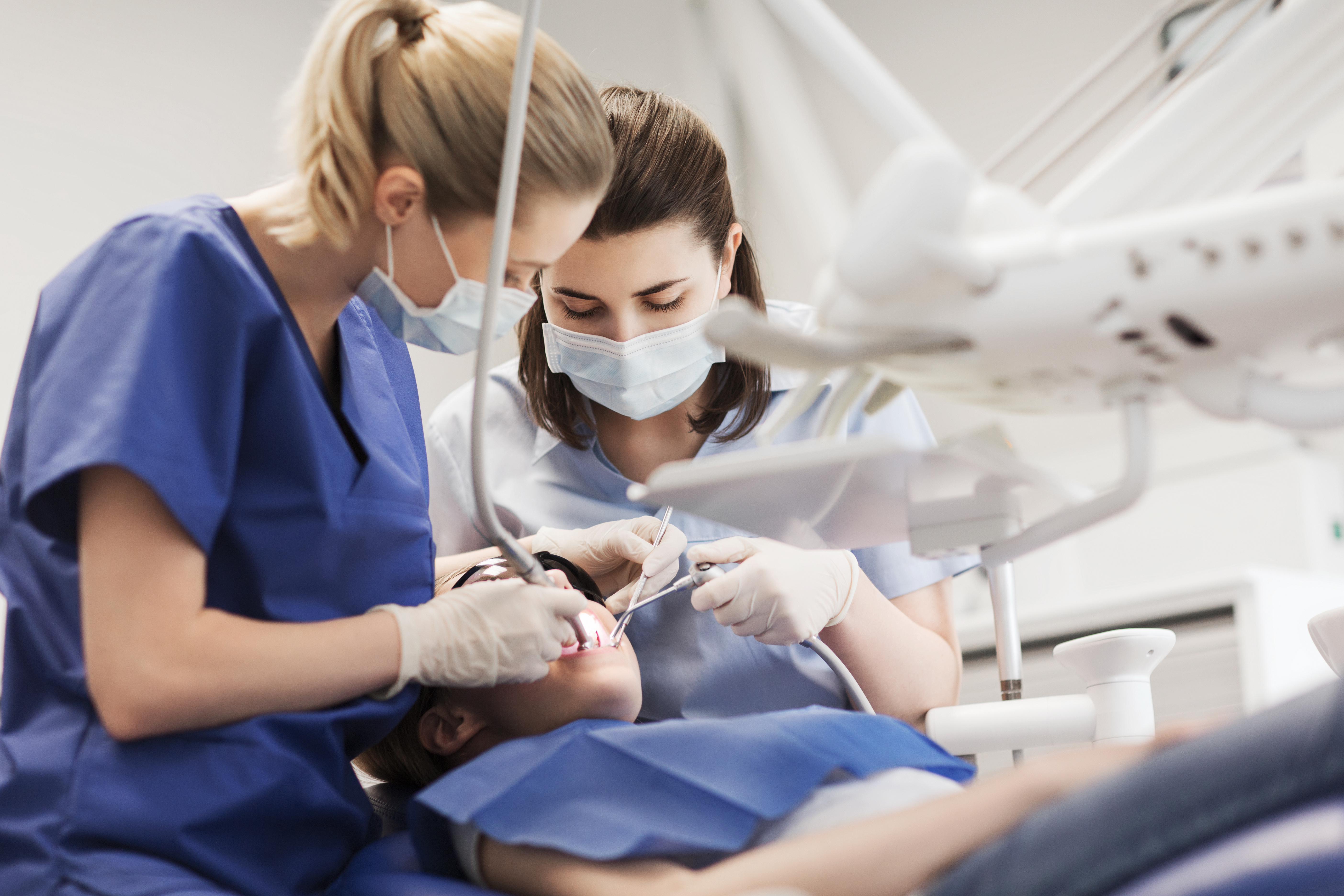 A dental assistant inspects the mouth of a patient